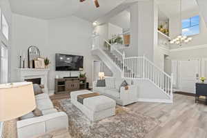 Living room with a high ceiling, ceiling fan with notable chandelier, and light hardwood / wood-style flooring