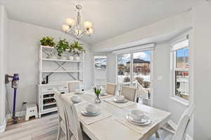 Dining space with vaulted ceiling, a chandelier, and light hardwood / wood-style floors