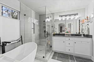 Bathroom featuring vanity, a textured ceiling, and separate shower and tub