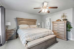 Bedroom featuring light carpet, ceiling fan, and ensuite bath