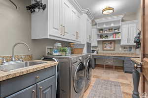 Washroom with sink, cabinets, and washing machine and clothes dryer