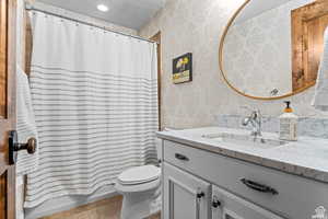 Full bathroom with shower / tub combo with curtain, vanity, a textured ceiling, tile patterned floors, and toilet