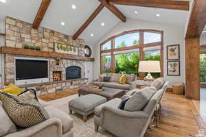 Living room with light hardwood / wood-style flooring, a fireplace, high vaulted ceiling, and beamed ceiling