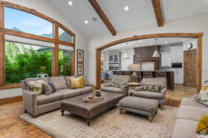 Living room featuring high vaulted ceiling, light hardwood / wood-style floors, and beamed ceiling