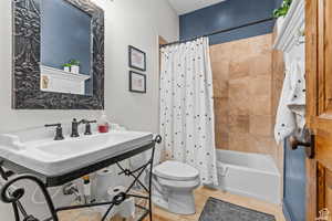 Full bathroom with sink, shower / tub combo, tile patterned floors, and toilet