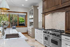 Kitchen with sink, white cabinetry, double oven range, dark stone counters, and decorative backsplash