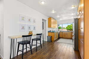 Kitchen featuring stainless steel appliances, dark hardwood / wood-style flooring, a textured ceiling, and a kitchen breakfast bar