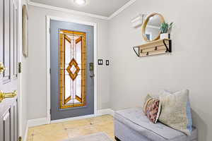 Tiled foyer featuring crown molding