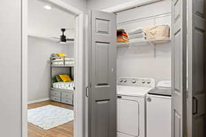 Laundry room with ceiling fan, separate washer and dryer, and light wood-type flooring