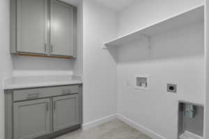 Washroom featuring cabinets, hookup for an electric dryer, light hardwood / wood-style floors, and hookup for a washing machine