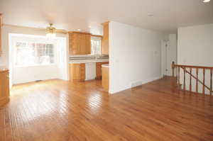 Unfurnished living room featuring sink, ceiling fan, and light hardwood / wood-style flooring