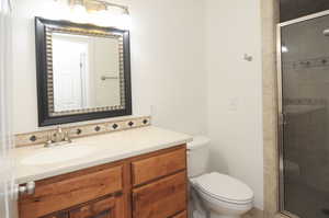 Bathroom with an enclosed shower, vanity, and toilet