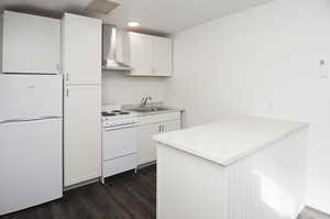 Kitchen with white cabinets, white appliances, sink, and wall chimney exhaust hood