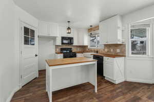 Kitchen featuring black appliances, wooden counters, and white cabinets