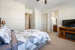 Bedroom with light carpet, connected bathroom, and ceiling fan