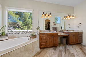 Bathroom featuring vanity, hardwood / wood-style floors, and tiled tub