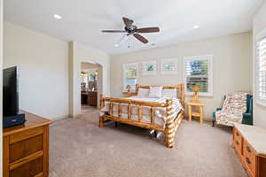 Bedroom with ensuite bath, light colored carpet, and ceiling fan