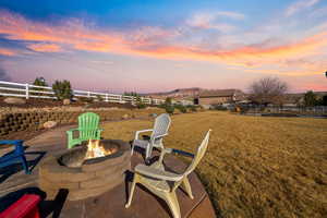 Patio terrace at dusk with a fire pit and a lawn