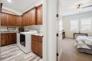 Clothes washing area with cabinets, ceiling fan, light carpet, and independent washer and dryer