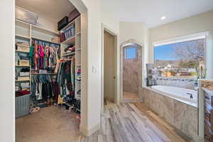 Walk in closet with light hardwood / wood-style flooring