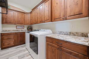 Laundry area with cabinets, washing machine and dryer, and light wood-type flooring