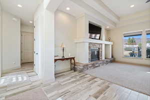 Unfurnished living room with a stone fireplace and light wood-type flooring