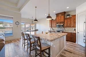 Kitchen featuring sink, tasteful backsplash, hanging light fixtures, a kitchen breakfast bar, and an island with sink