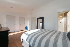 Bedroom with dark wood-type flooring, ensuite bath, and lofted ceiling