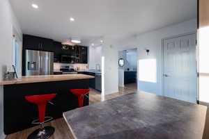 Kitchen featuring sink, a breakfast bar area, light wood-type flooring, appliances with stainless steel finishes, and kitchen peninsula