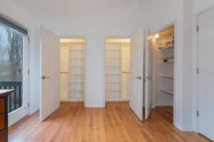 Unfurnished bedroom featuring lofted ceiling, a walk in closet, light hardwood / wood-style floors, and a closet