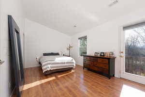 Bedroom featuring wood-type flooring, vaulted ceiling, and access to exterior