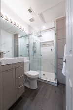 Bathroom featuring hardwood / wood-style flooring, vanity, toilet, and walk in shower