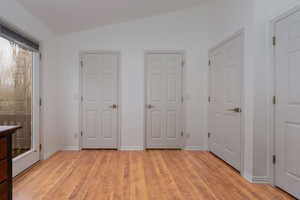 Unfurnished bedroom featuring vaulted ceiling and light wood-type flooring