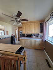 Kitchen featuring light brown cabinetry, light tile patterned floors, black refrigerator with ice dispenser, and ceiling fan