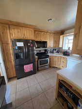 Kitchen with light tile patterned flooring, sink, and black appliances