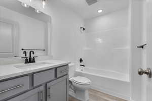 Full bathroom with shower / tub combination, wood-type flooring, vanity, and toilet