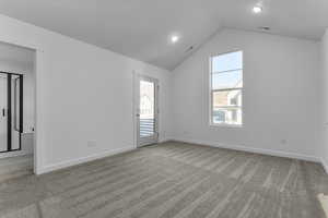 Carpeted spare room featuring lofted ceiling