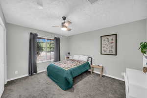 Bedroom with ceiling fan, carpet floors, and a textured ceiling