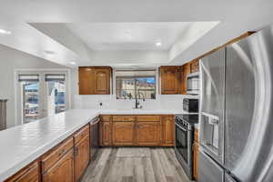 Kitchen with appliances with stainless steel finishes, tasteful backsplash, sink, light hardwood / wood-style floors, and french doors