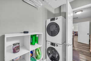 Laundry room with stacked washer and dryer, hardwood / wood-style floors, and a textured ceiling