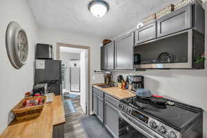 Kitchen featuring gray cabinets, appliances with stainless steel finishes, sink, and butcher block countertops