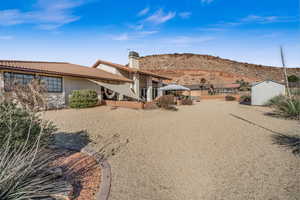 Back of house with a mountain view and a storage unit