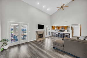 Living room with french doors, ceiling fan, a fireplace, and hardwood / wood-style flooring