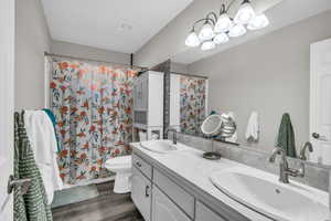 Bathroom with vanity, toilet, curtained shower, and hardwood / wood-style floors