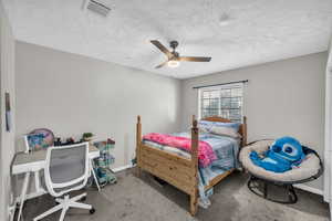 Carpeted bedroom featuring a textured ceiling and ceiling fan