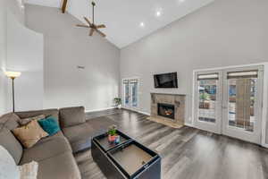 Living room with hardwood / wood-style floors, a fireplace, high vaulted ceiling, and french doors