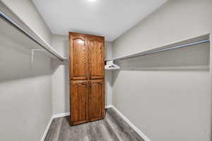 Walk in closet with wood-type flooring