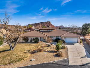 Ranch-style house with a garage, a mountain view, and a front lawn