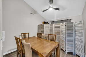 Dining room featuring ceiling fan, dark hardwood / wood-style flooring, and vaulted ceiling