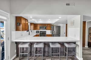 Kitchen featuring appliances with stainless steel finishes, a raised ceiling, sink, and kitchen peninsula